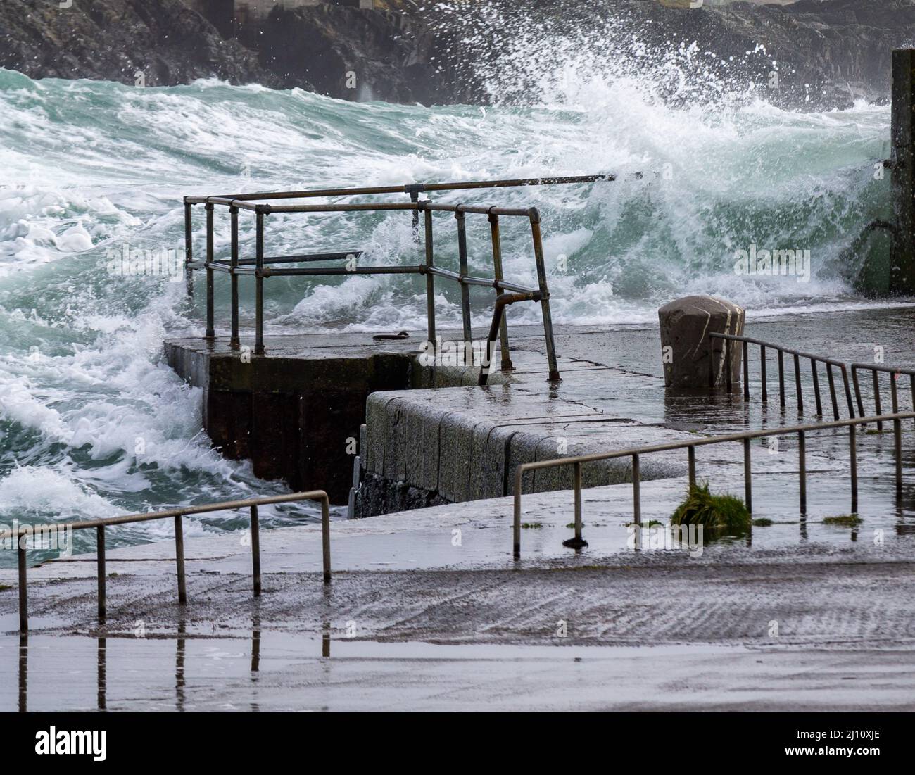 Atlantic storm waves breaking over pier safety barrier hand rails Stock Photo