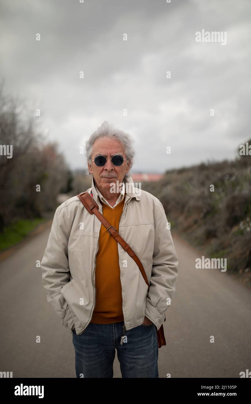 A man, with gray hair, standing, enjoys a walk in the countryside, in spring, in a rural area of the Campo de Borja region, Zaragoza province, Aragon, Stock Photo
