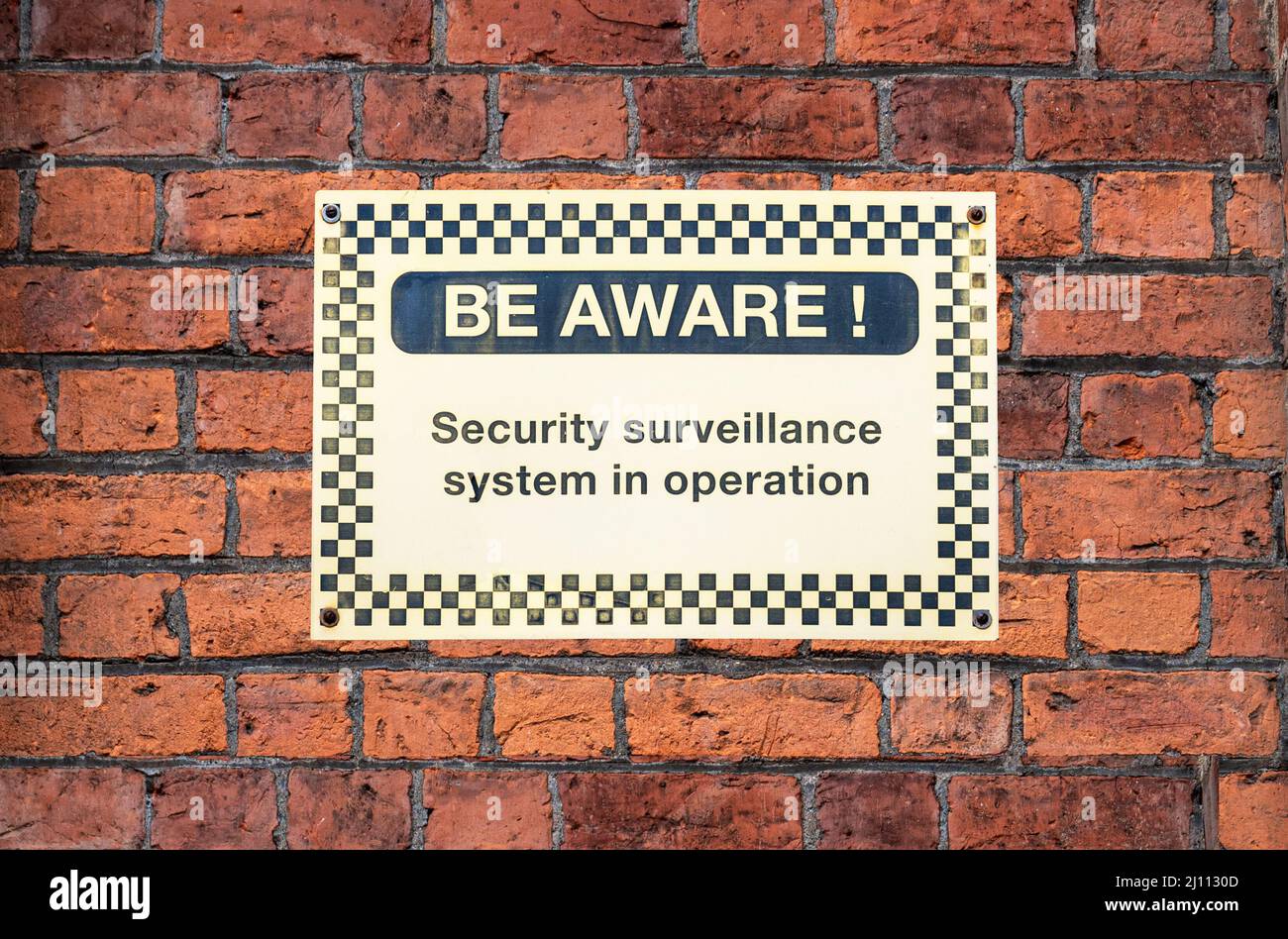 BE AWARE - security sign on brick wall background Stock Photo