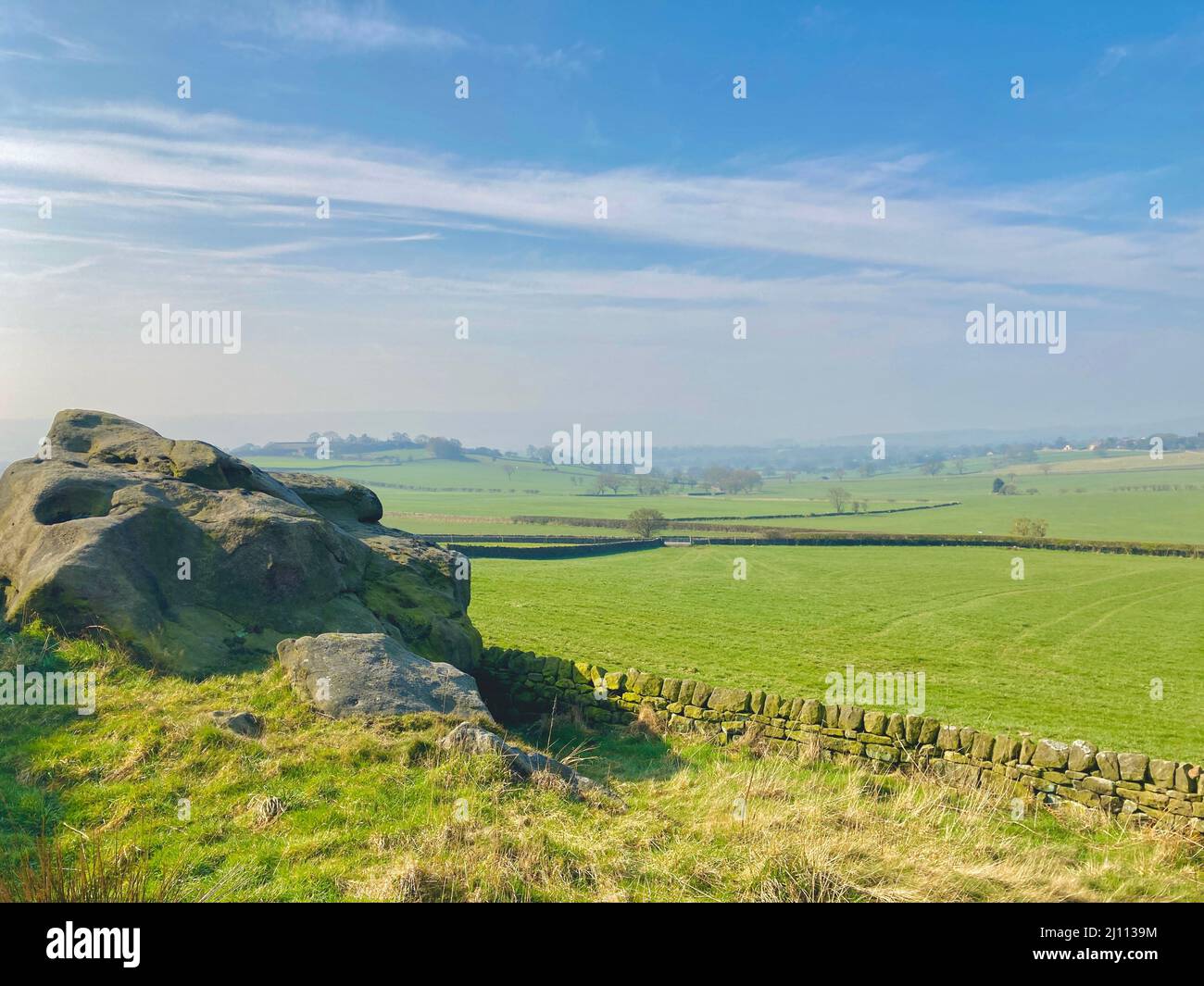 Scenic landscape blue sky view over green fields from Almscliffe Crag a Millstone Grit outcrop in North Yorkshire countryside. Stock Photo