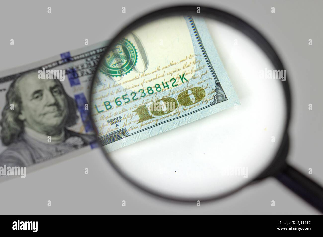 Magnifying glass on a pile of 100 dollar banknotes. Checking suspicious