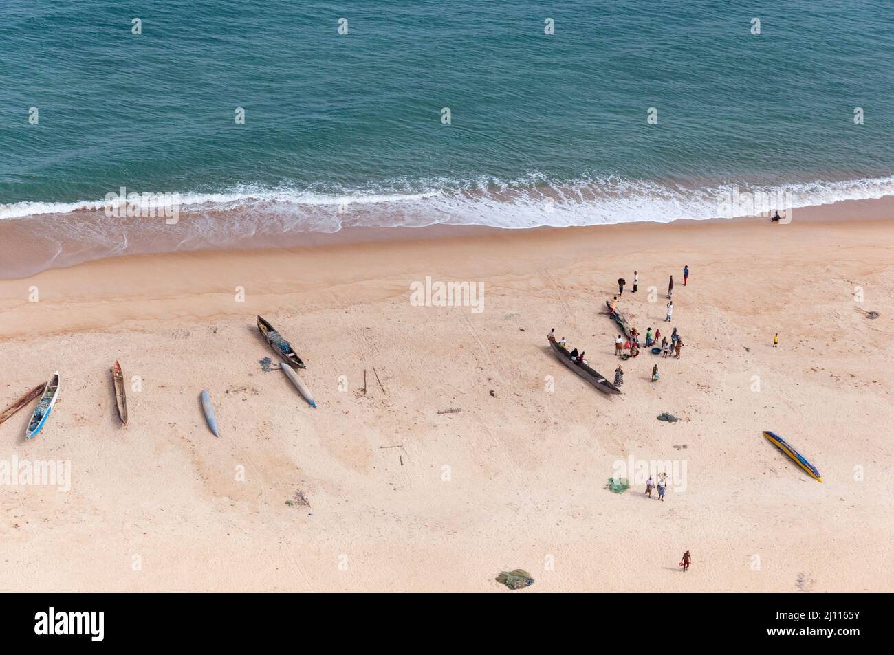 A Liberian beach bustling with activity. Dugout canoes, people and fishing nets captured midday, on a ferry flight from Monrovia to Freetown. Stock Photo
