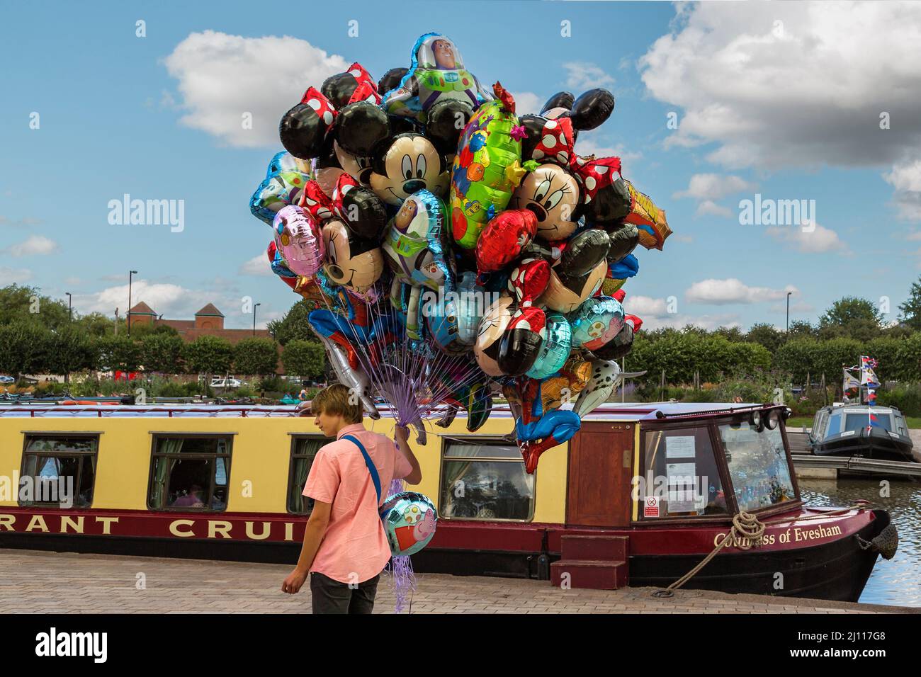 A young man selling helium filled foil balloons featuring cartoon