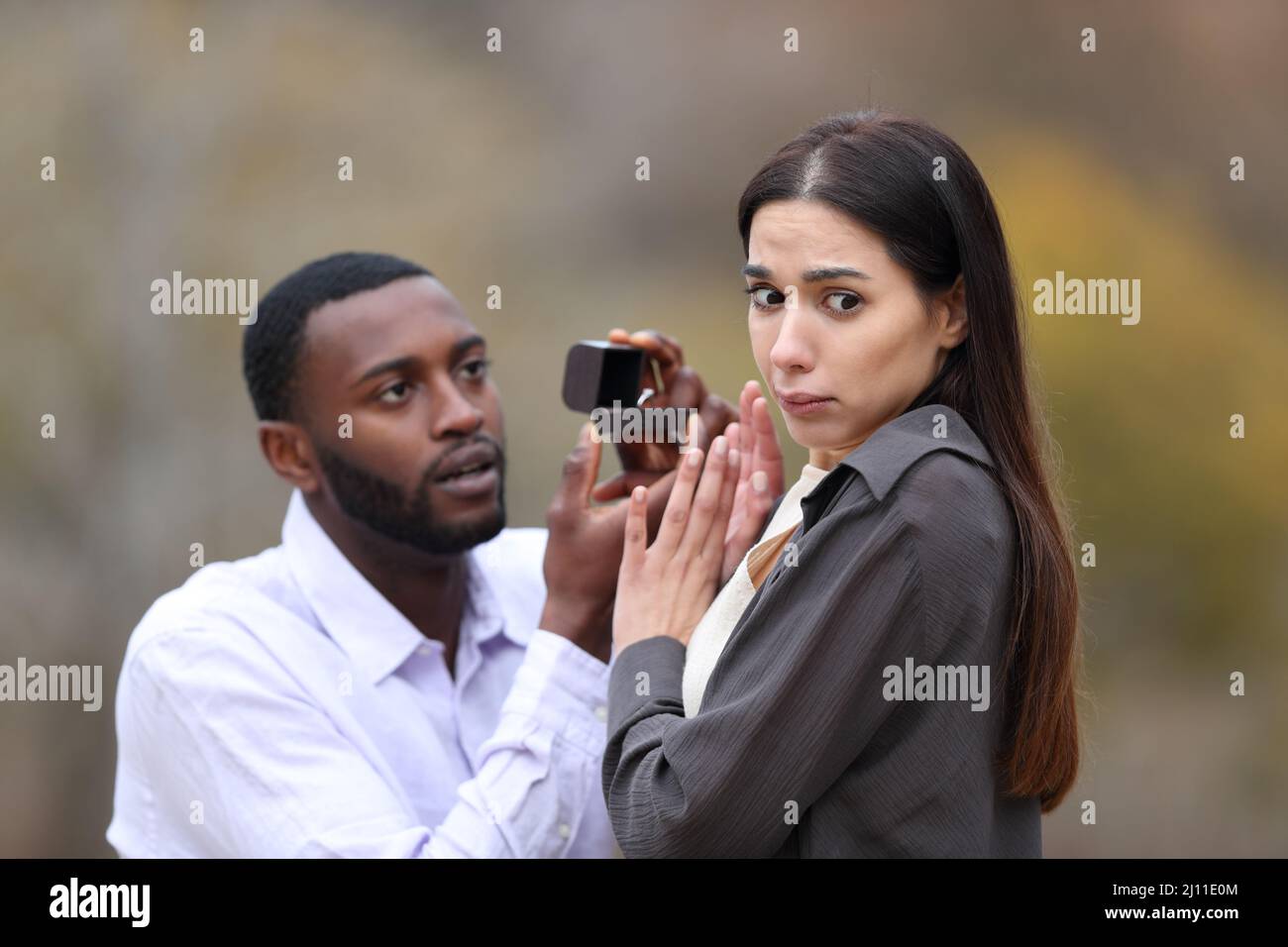 Scared woman rejecting her surprised boyfriend after marriage proposal in a park Stock Photo