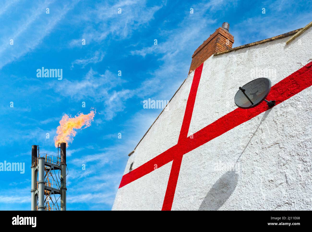 House wall painted with England flag next to gas flare stack. Rising energy, gas, prices. Cost of living crisis, North Sea gas, UK economy, concept. Stock Photo