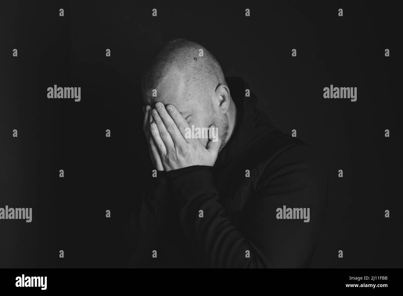 Sad man sitting in dark room. Depression and anxiety concept Stock