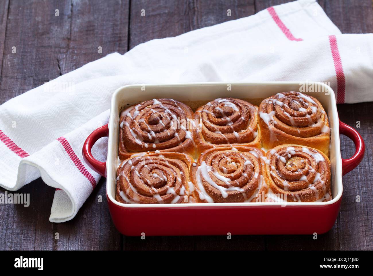 Traditional cinnamon buns with icing on a wooden table. Rustic style. Stock Photo