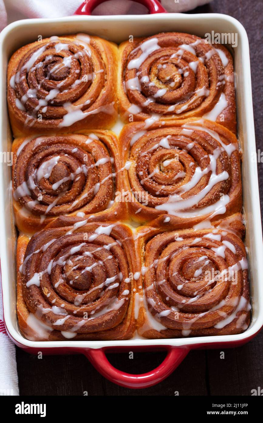 Traditional cinnamon buns with icing on a wooden table. Rustic style. Stock Photo