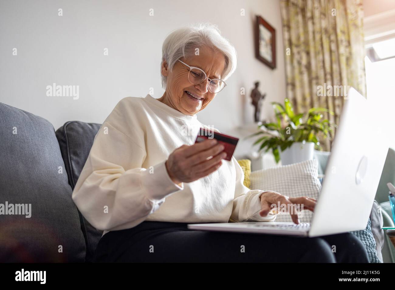 Senior woman doing online shopping on laptop at home Stock Photo