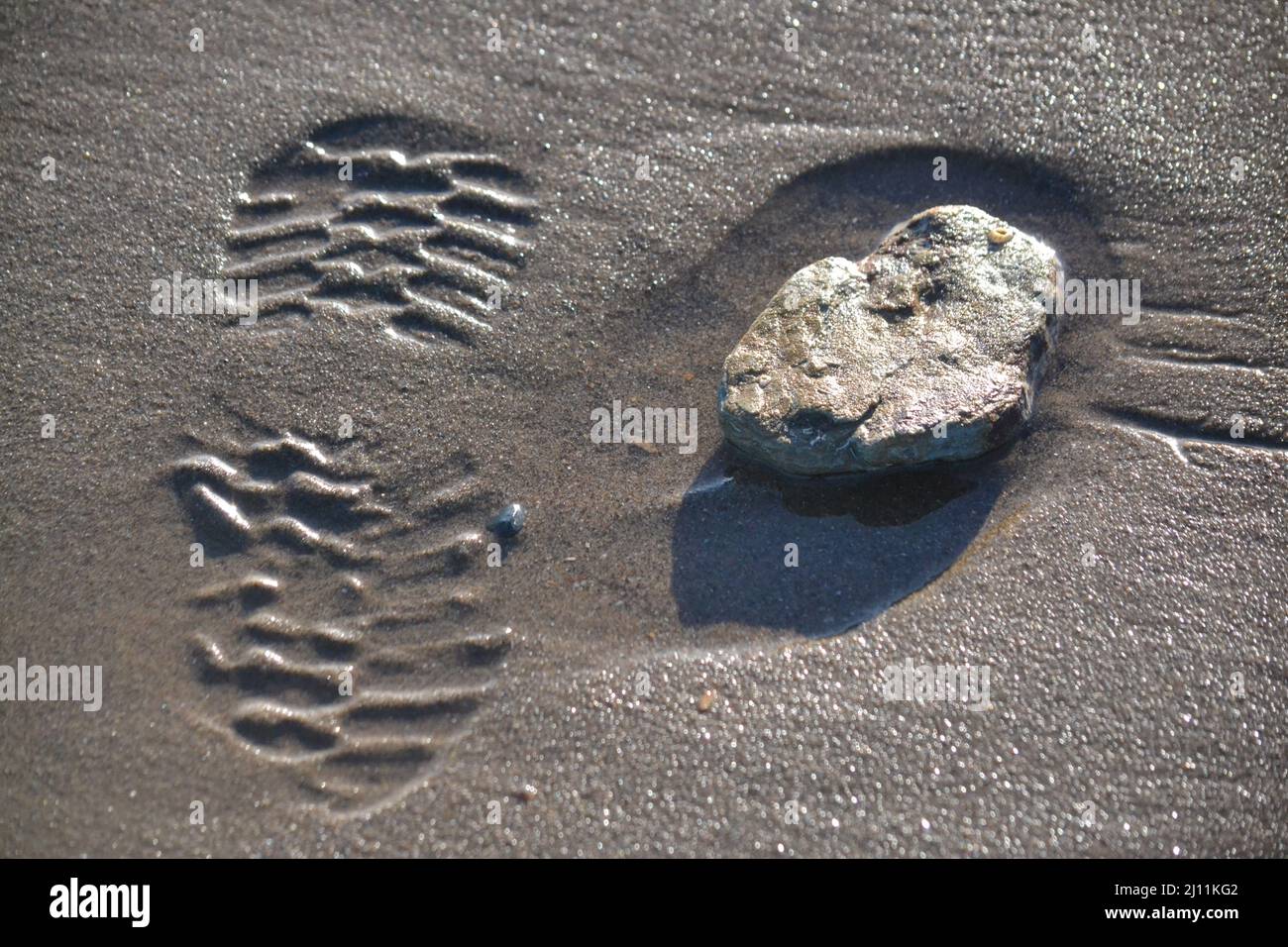 Shoe Print Next To A Stone - Footprint On A Sandy Beach - Sunny Day - Sole Print - Beach Walking Holidays - Winter Sunshine - North Yorkshire - UK Stock Photo