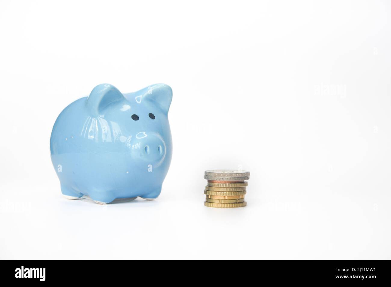Photo of a blue piggy bank and coins, cash or money on white background ...