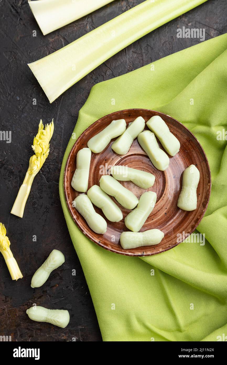 Jelly celery candies on black concrete background and green linen