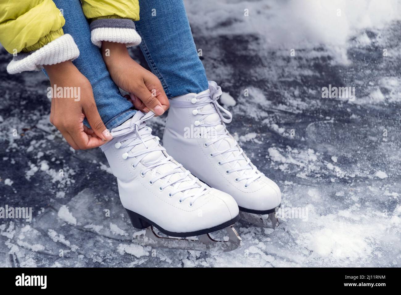 Closeup of African American woman tying shoelaces on ice skates Stock Photo