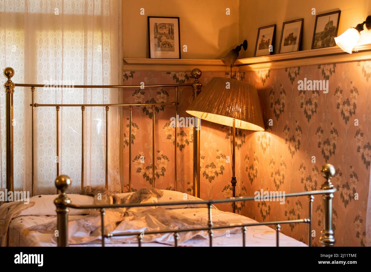 Feminine bedroom with brass bed and antique pink floral wallpaper in the Riordan Mansion in Flagstaff, Arizona, U.S.A. Stock Photo