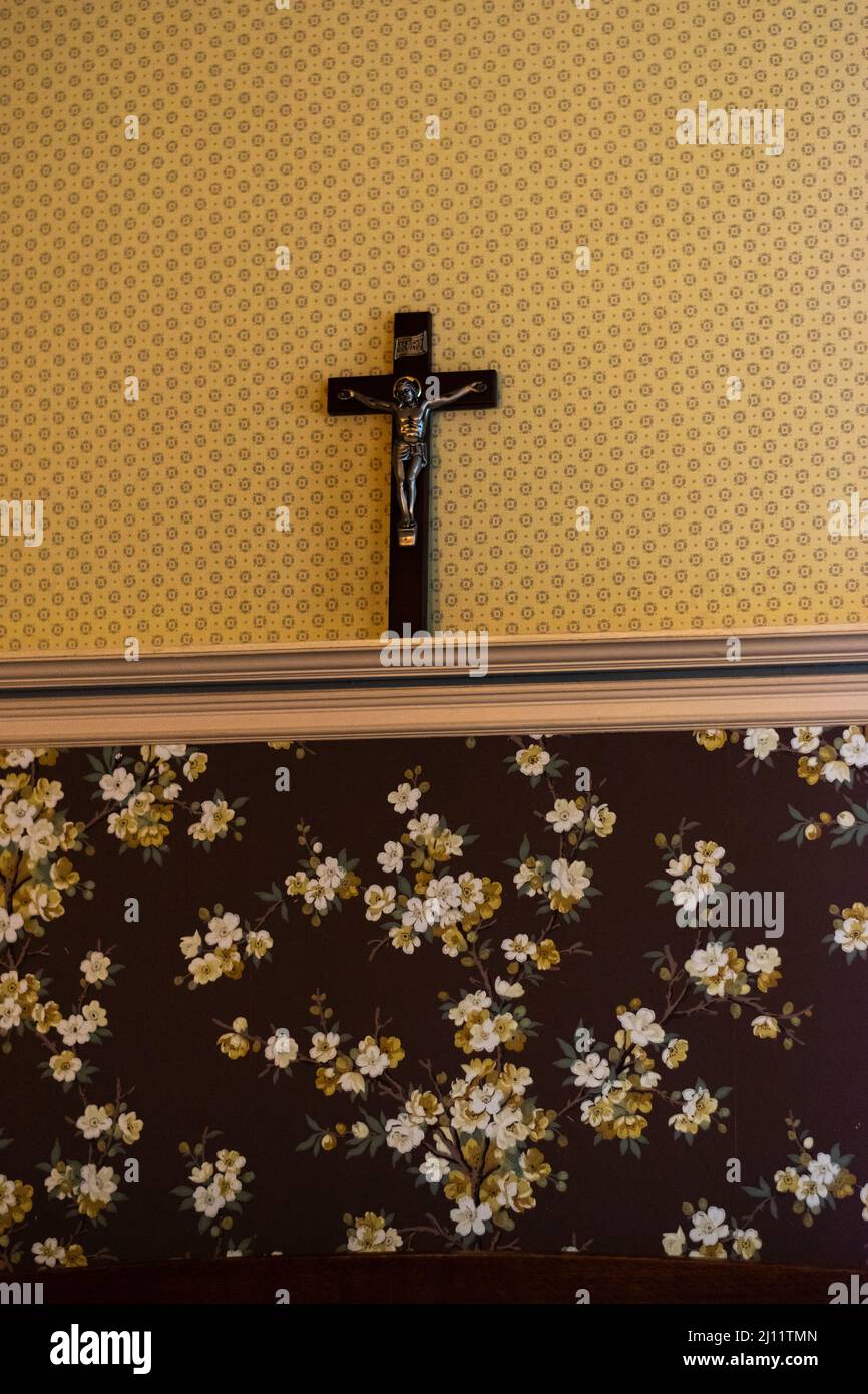 Wall adorned with antique wallpaper and cross inside the Riordan Mansion in Flagstaff, Arizona, U.S.A. Stock Photo