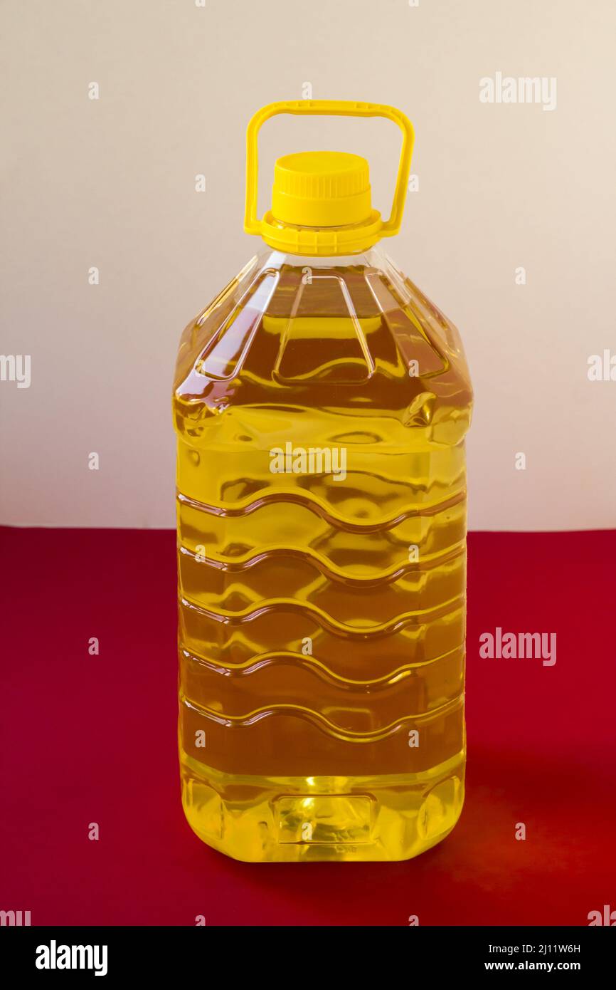 Five liter sunflower oil in a plastic bottle on red surface,vertical image Stock Photo