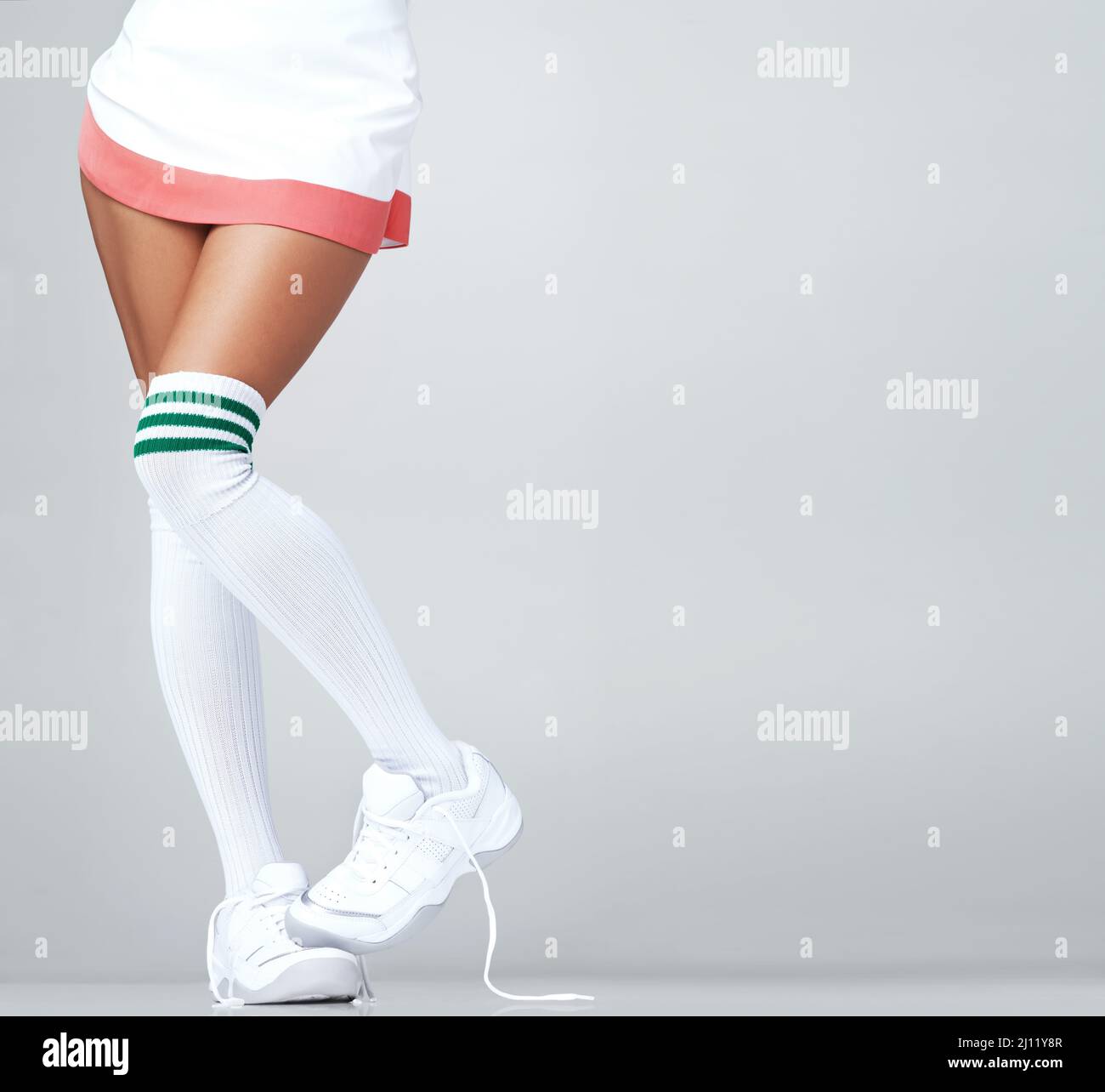 Showing my shyness through my feet. Close up of womans legs in a skirt and  long socks with trainers on with copyspace Stock Photo - Alamy