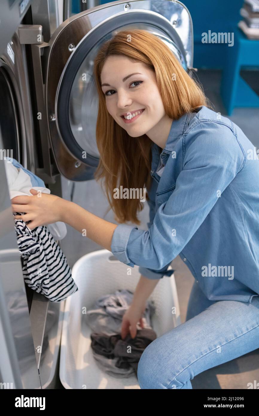 young woman in a launderette washing her dirty laundry Stock Photo Alamy