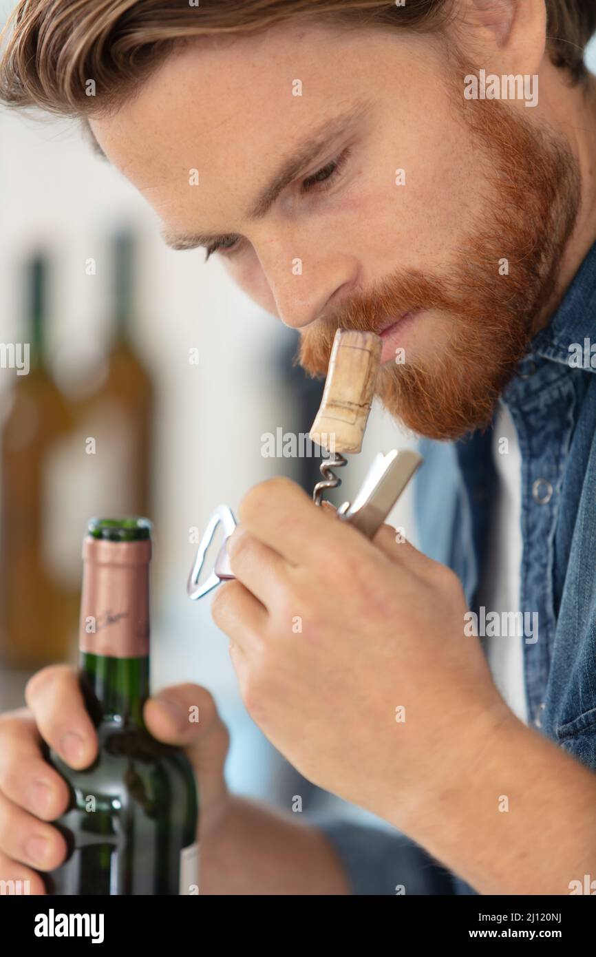 a man sniffing the cork of a bottle of wine Stock Photo Alamy