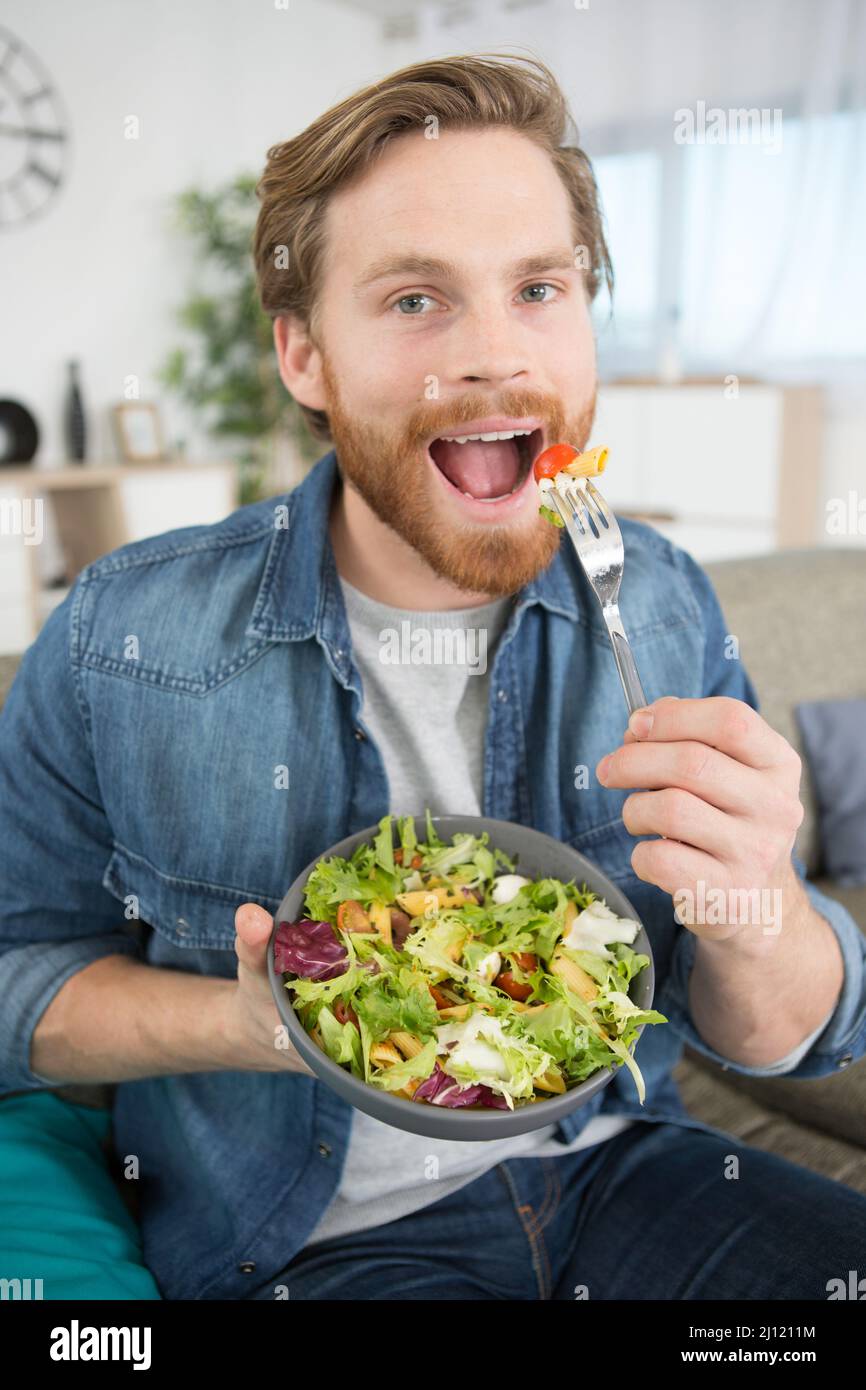 happy man eating salad at home Stock Photo Alamy