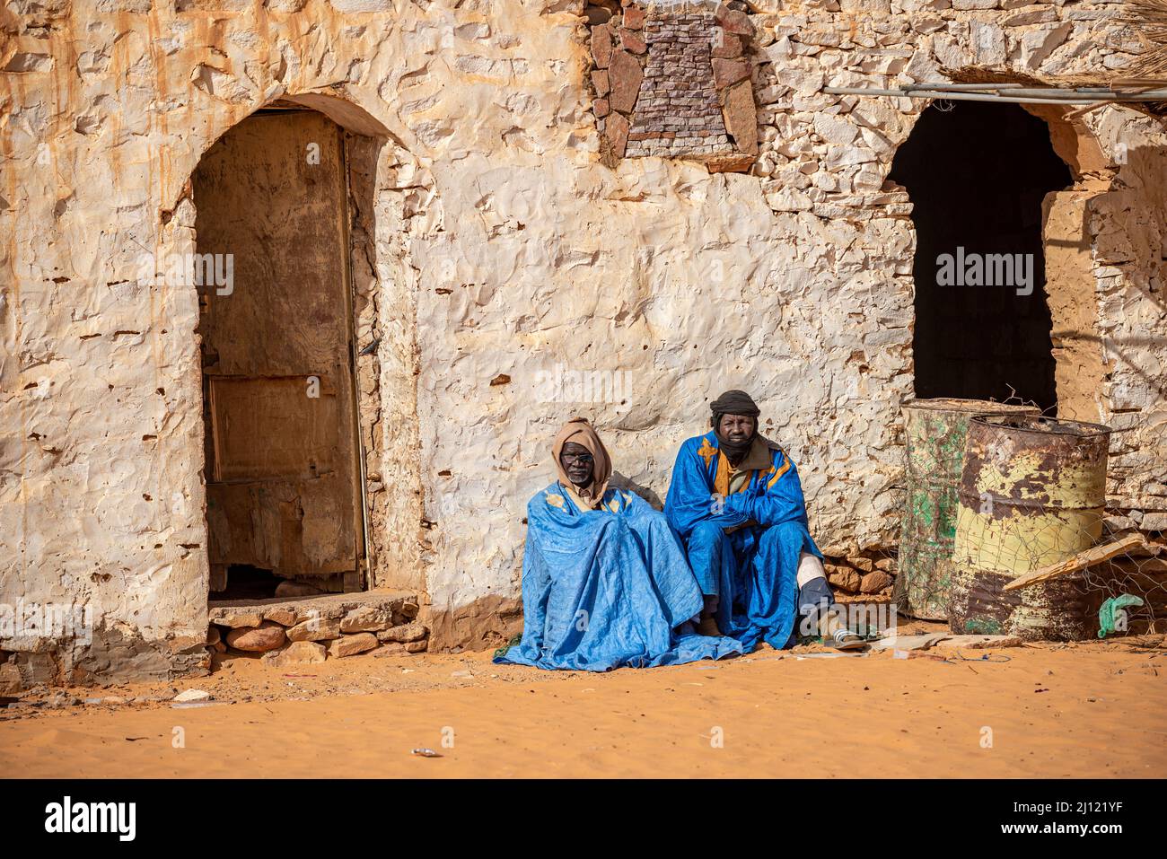 Two adult men in traditional wear sitting in front of a traditional house, Chinguetti, Mauritania Stock Photo