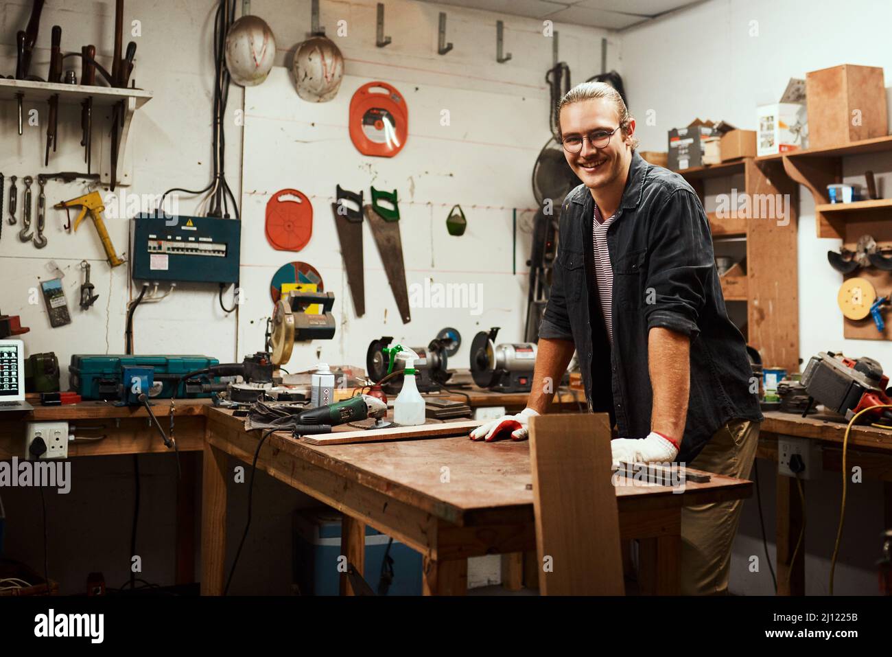 Always in a good mood when hes here. Portrait of a cheerful young male carpenter taking a quick break while working inside of his workshop at home Stock Photo