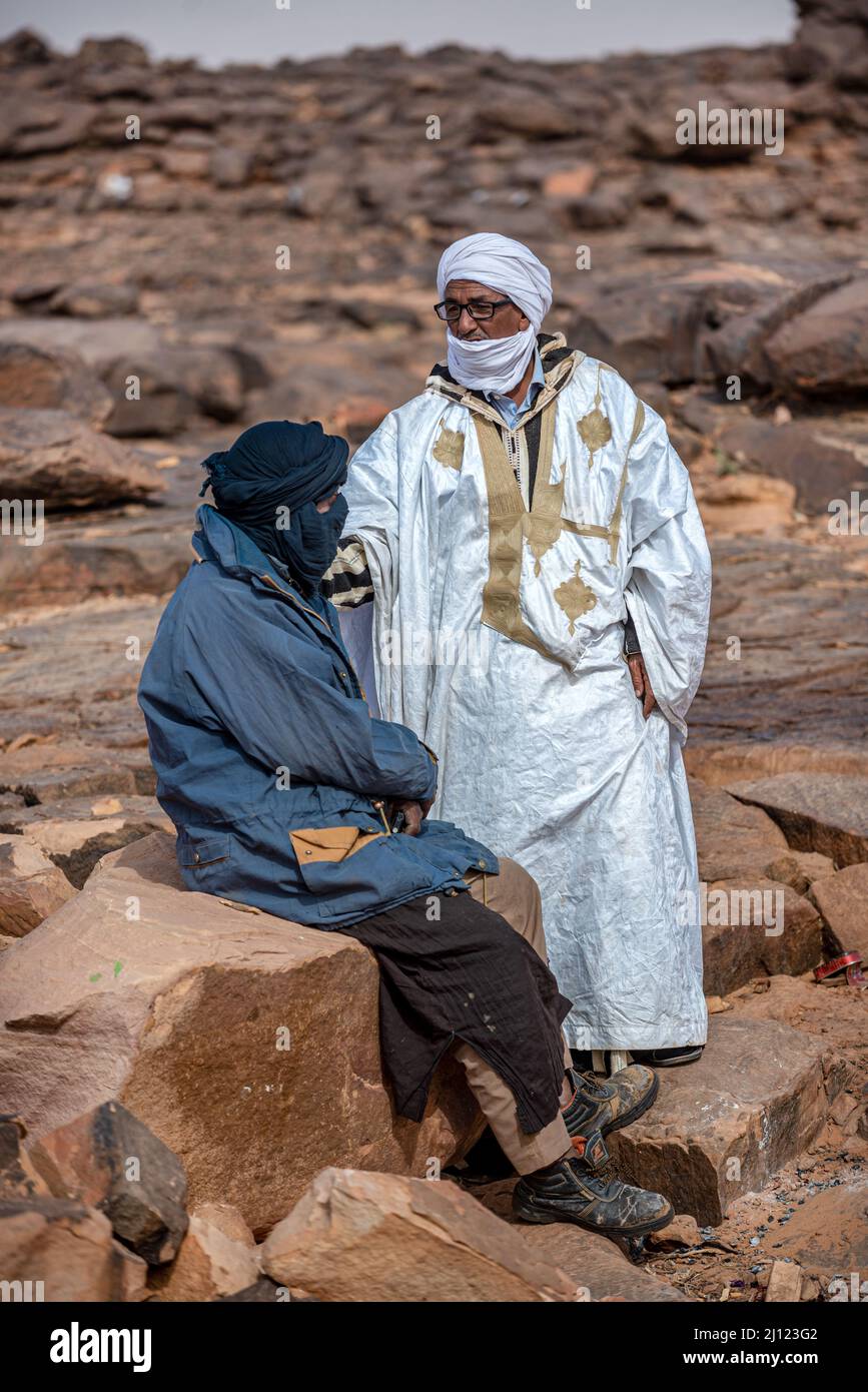 Two Mauritanian men with turbans talking in a rocky landscape, Asrar Region, Mauritania Stock Photo