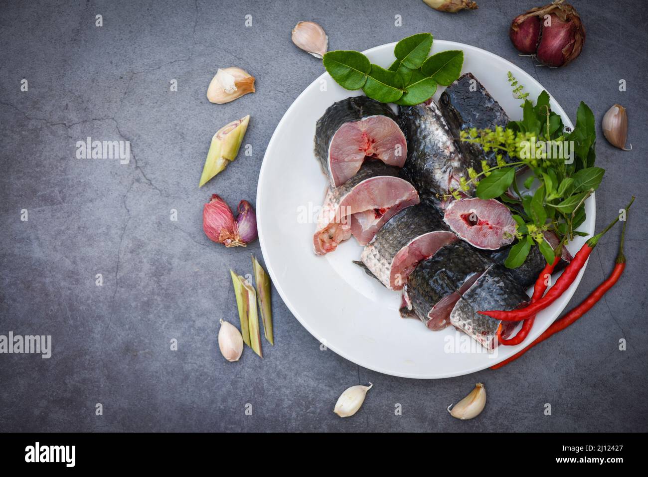 Snakehead fish for cooking food, striped snakehead fish chopped with ingredients herb and spices on white plate and table kitchen background, Fresh ra Stock Photo