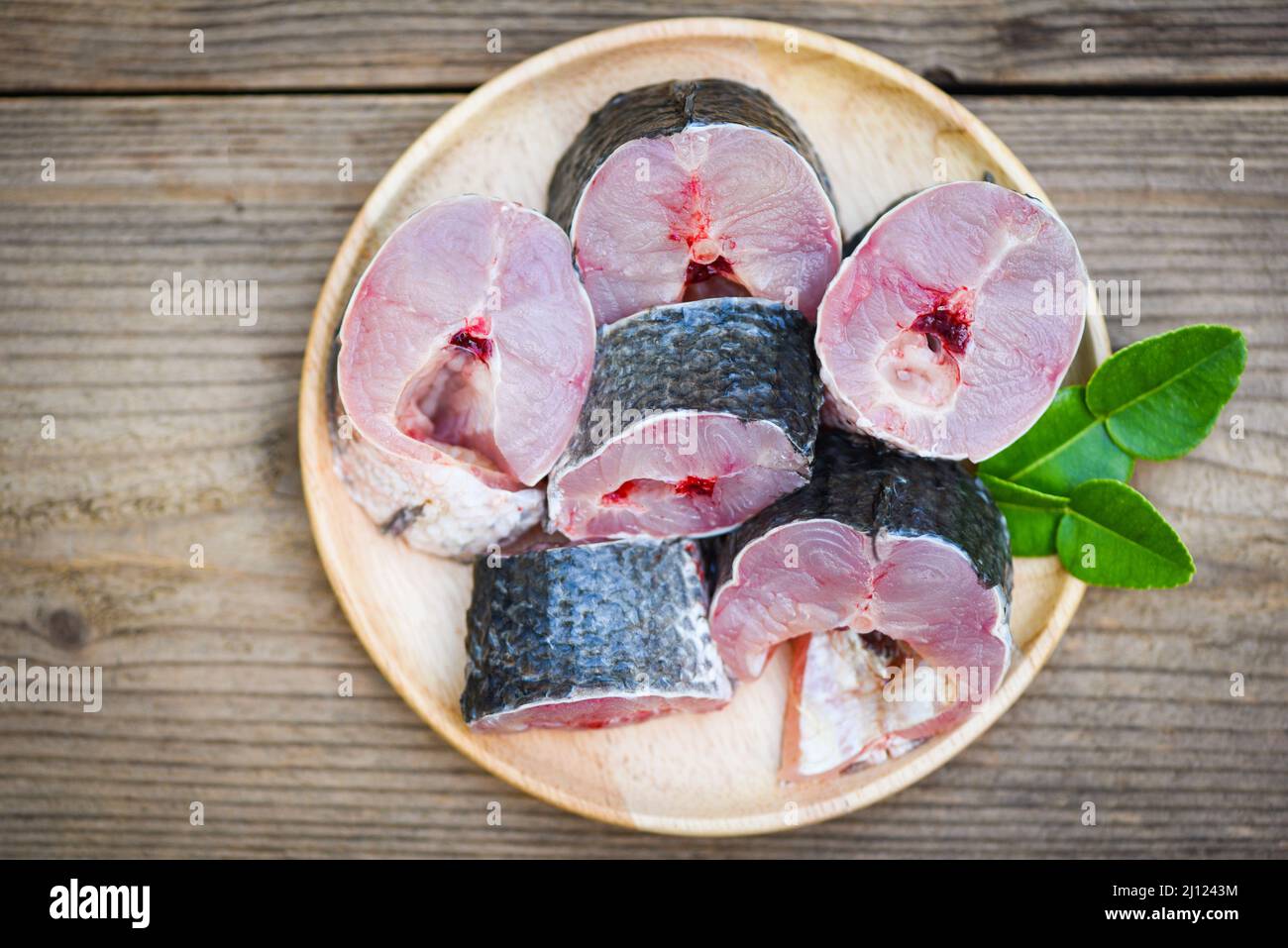 Snakehead fish for cooking food, striped snakehead fish chopped with ingredients kaffir lime leaves on plate and wooden table kitchen background, Fres Stock Photo