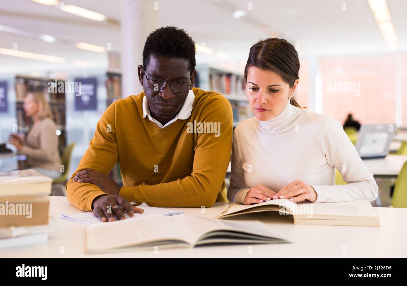 People reading and making notes while preparing for exam in library Stock Photo