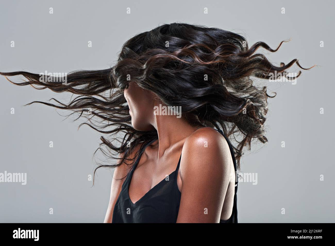 Now this is a hairstyle. Studio shot of a young woman with beautiful hair isolated on gray. Stock Photo
