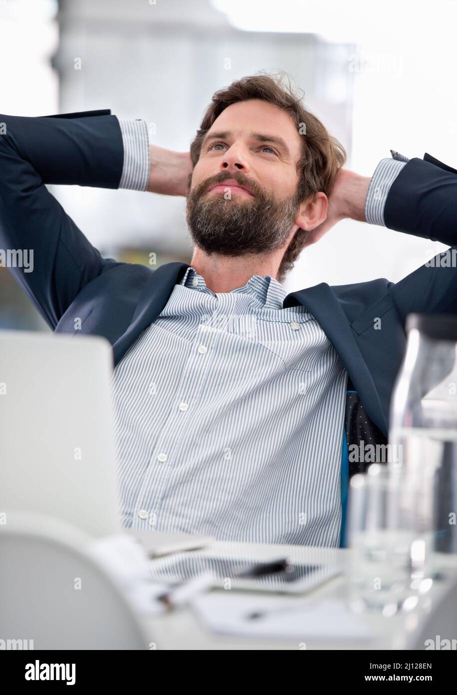 Dreaming big.... Shot of a young businessman looking thoughtful while sitting at his office desk. Stock Photo