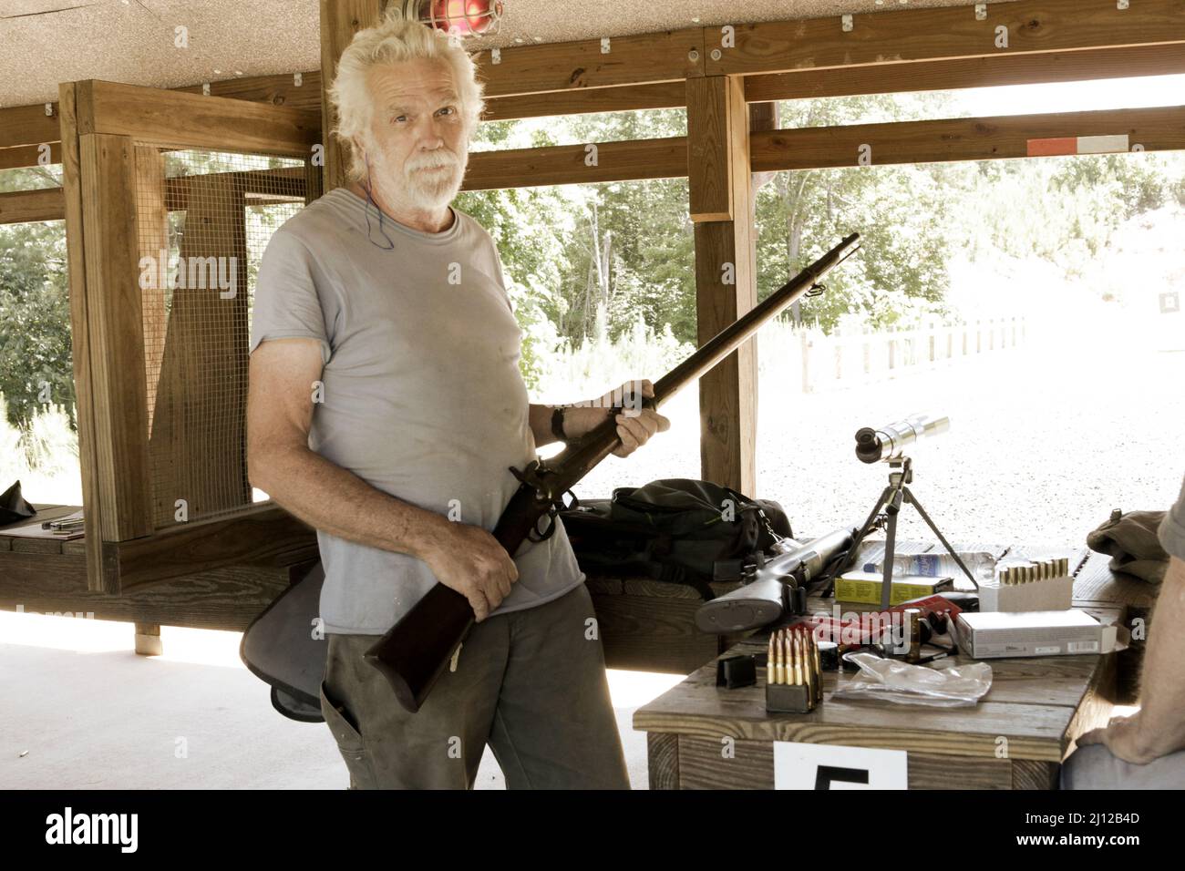 Old man at gun range with old gun Stock Photo