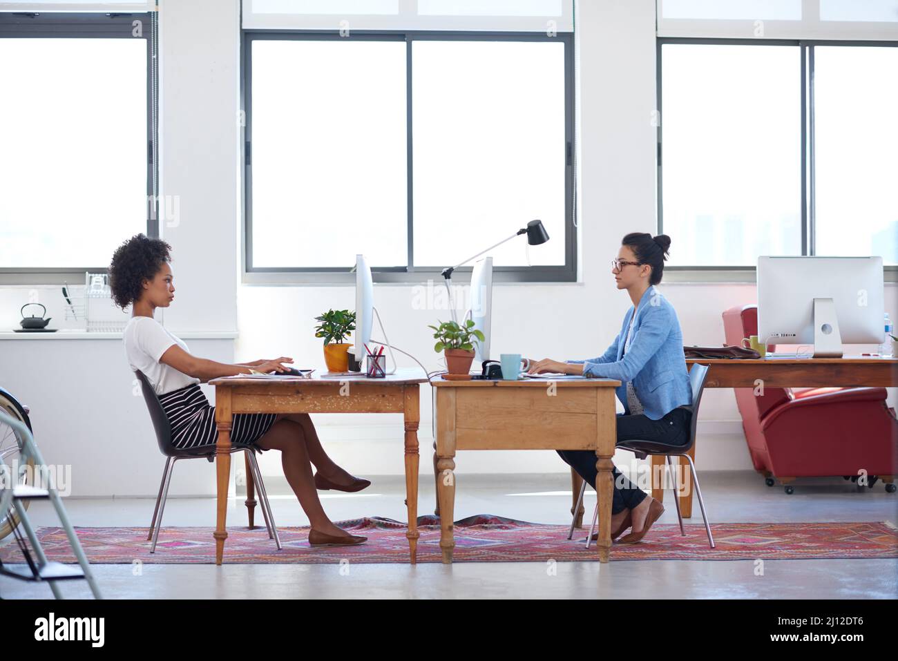 Creative space for contemporary business. Wide angle image of two female creative professionals in an open plan office space. Stock Photo