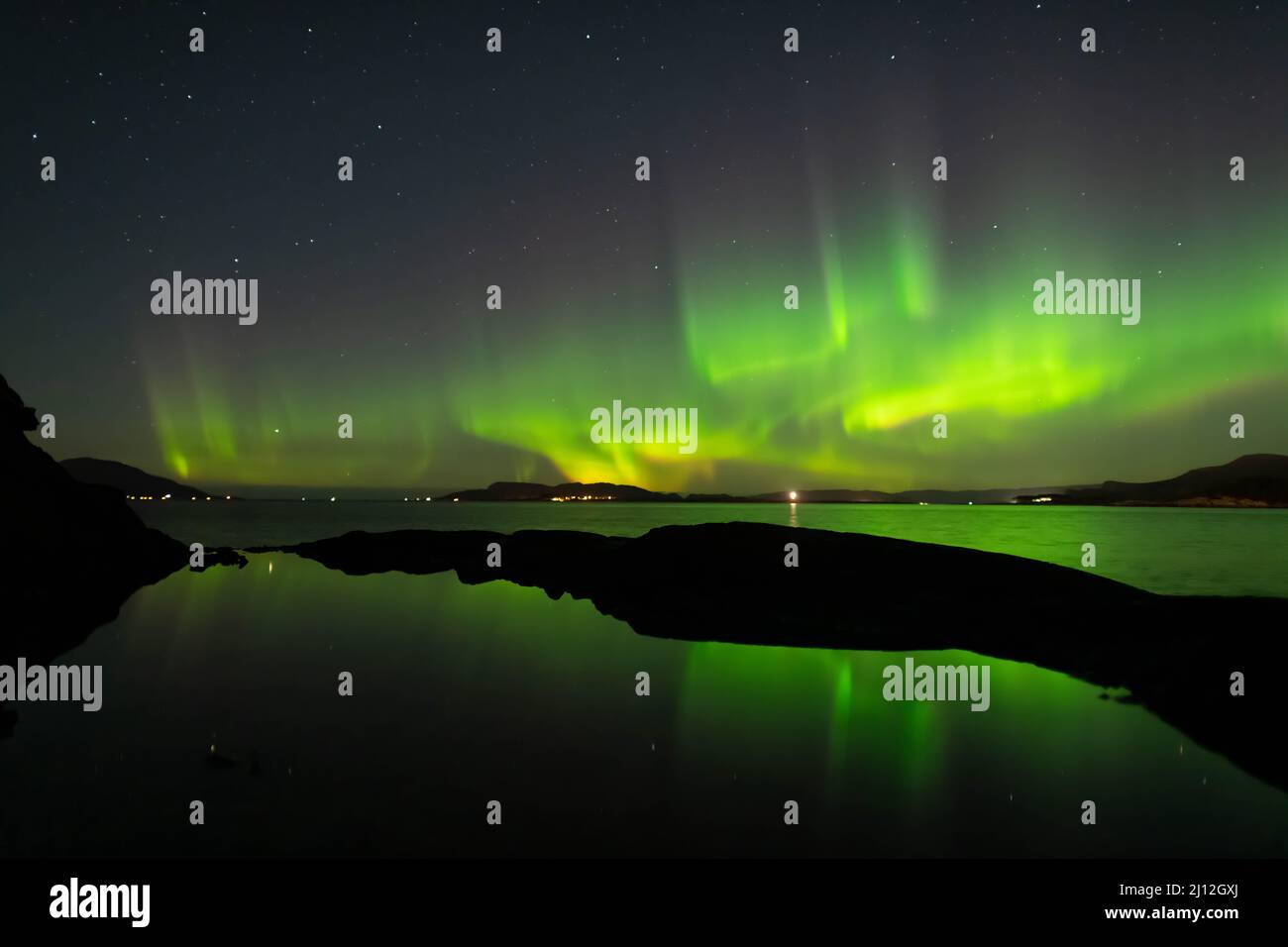 Green Northern Lights in sky at night reflecting in water Stock Photo ...
