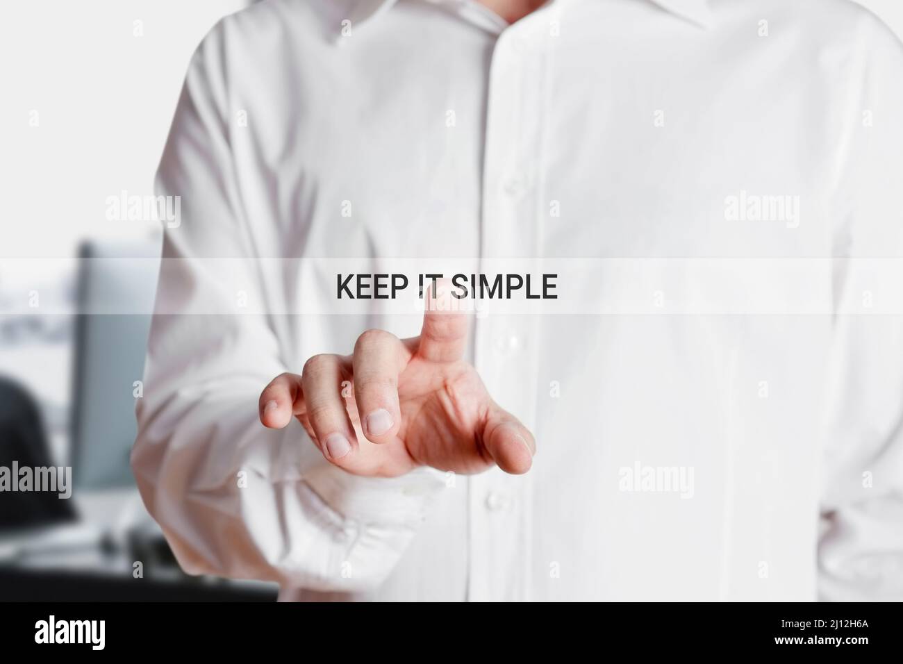 Businessman presses on virtual touch screen with the words keep it simple. Business strategy or principal concept. Stock Photo