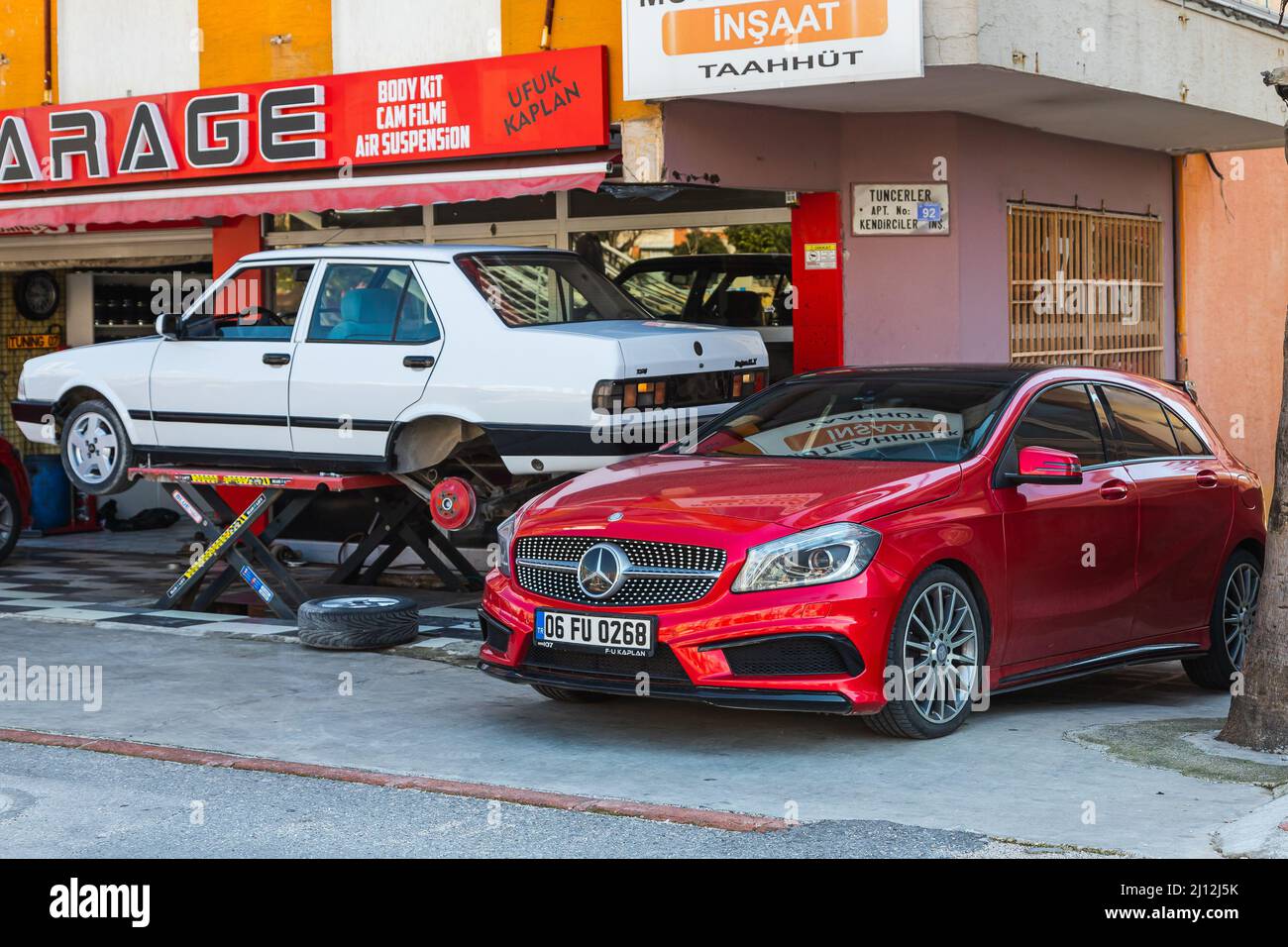 Antalya; Turkey – March 04 2022: yellow Tofas Dogan car on a lift at a tire shop  and red  Mercedes-Benz A-class Stock Photo