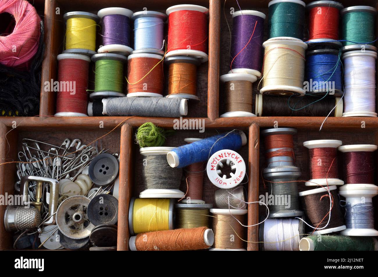 Sonderborg Denmark - March 14, 2022: View into a workbasket with spools of sewing thread in many colours, a M�lnlycke spool is seen. Stock Photo