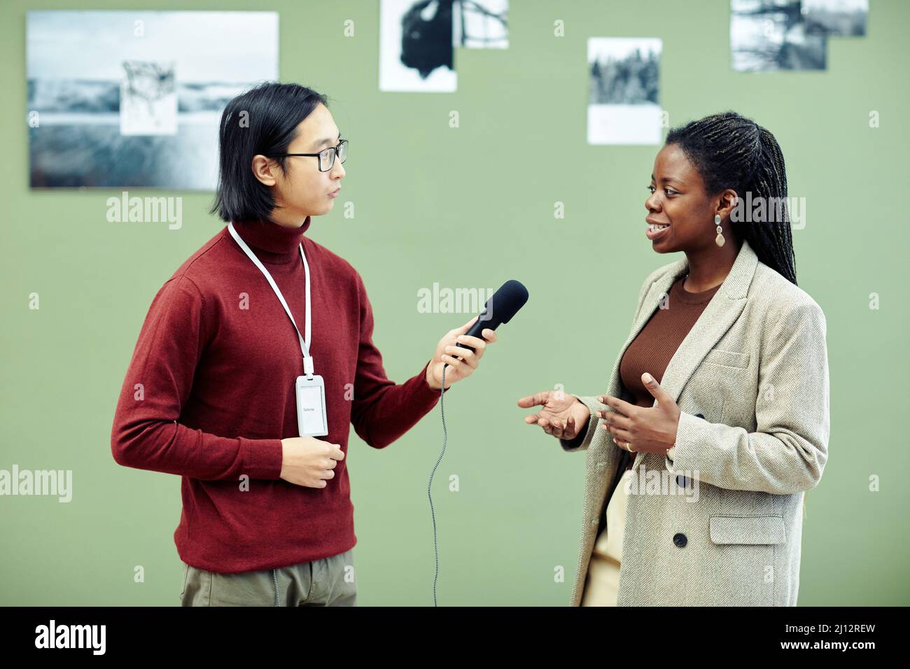 Young Asian art gallery worker taking interview of modern cheerful