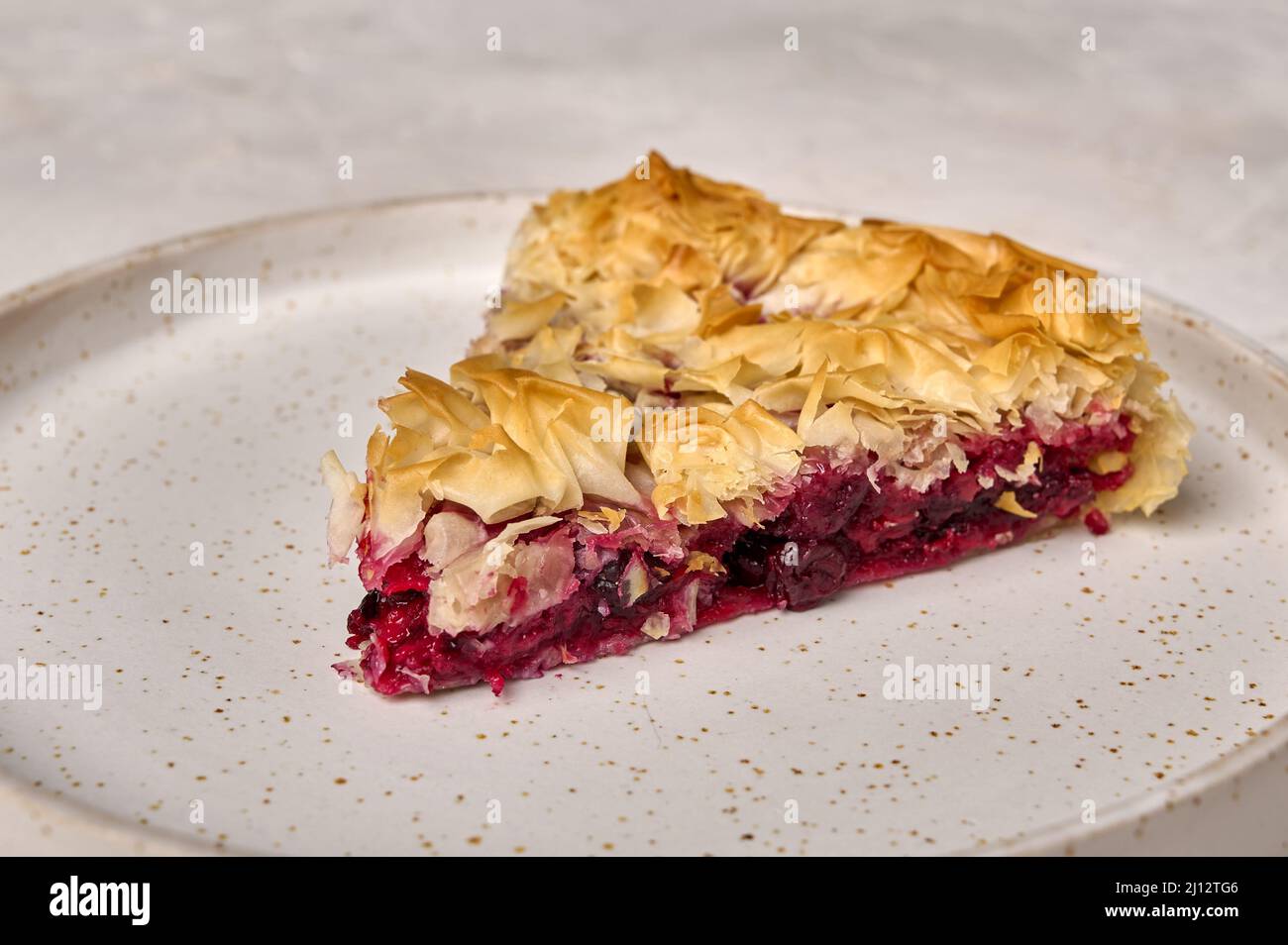 Piece of homemade cherry pie from filo dough on white plate. Selective focus, close up Stock Photo