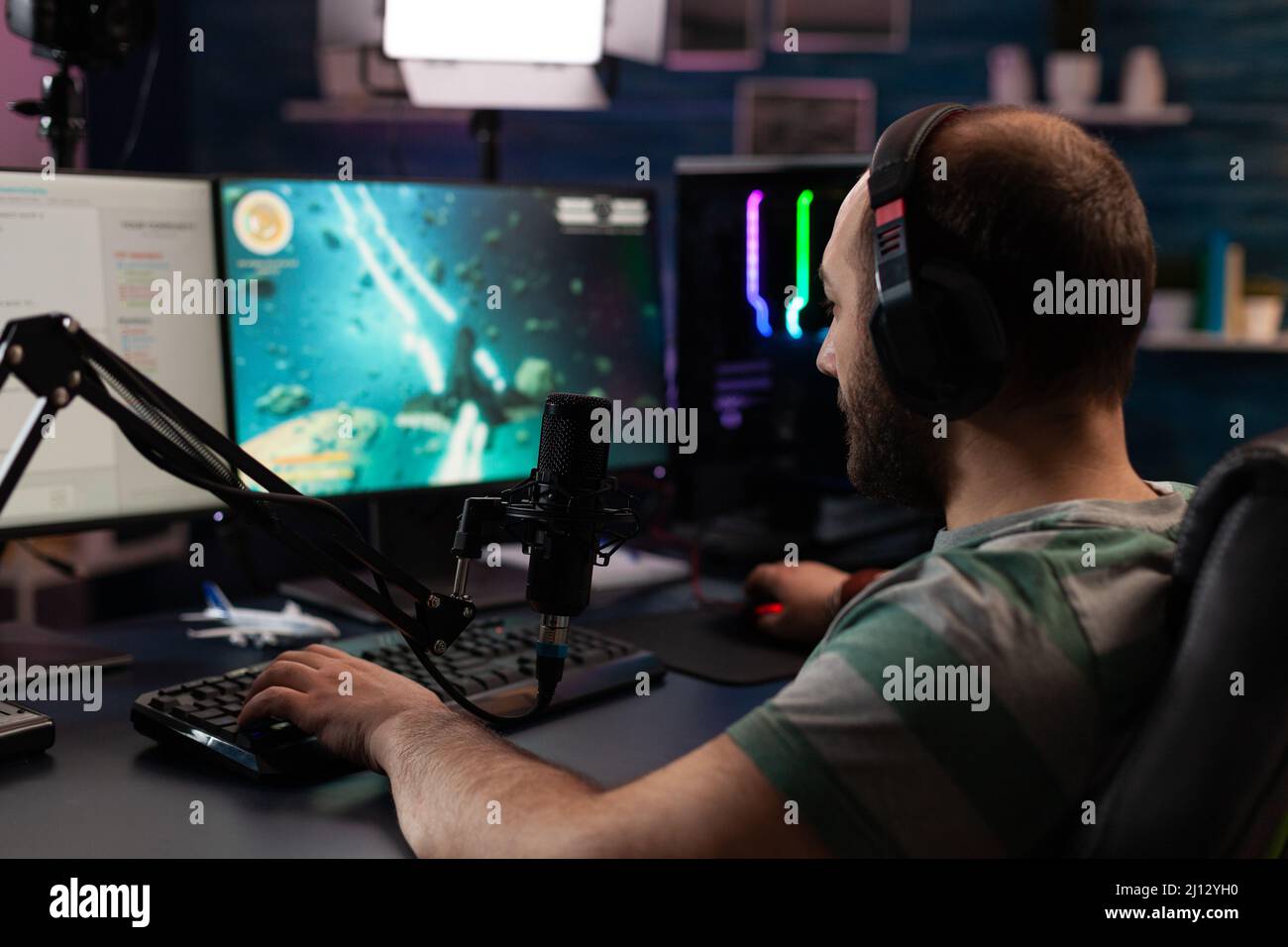 Person playing video games with controller on computer. Player using  joystick and wearing headphones to play online game on monitor. Modern man  using gaming equipment to have fun. Stock Photo