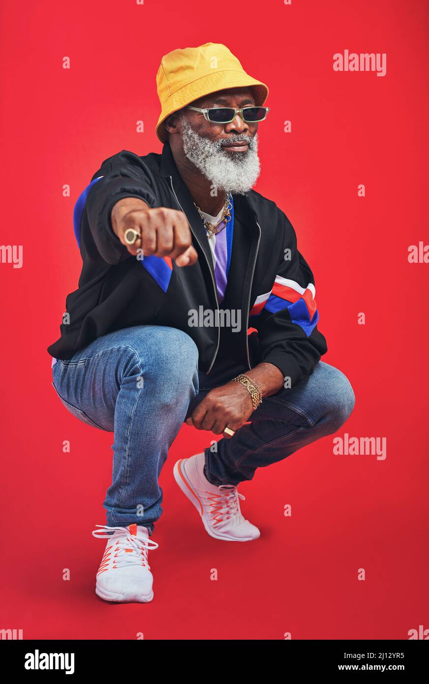 In order to be irreplaceable, one must always be different. Studio shot of a senior man wearing retro attire while posing against a red background. Stock Photo