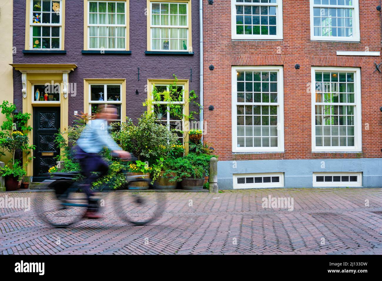 Bicycle rider cyclist man on bicycle very popular means of transoirt in Netherlands in street of Delft, Netherlands Stock Photo