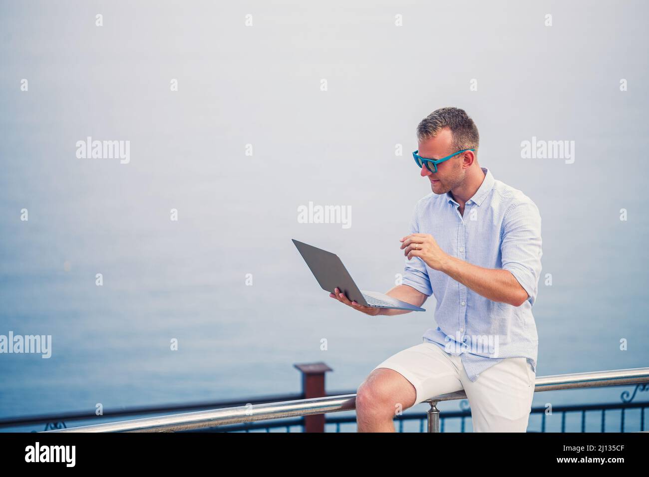 Young successful male businessman working with laptop on vacation by