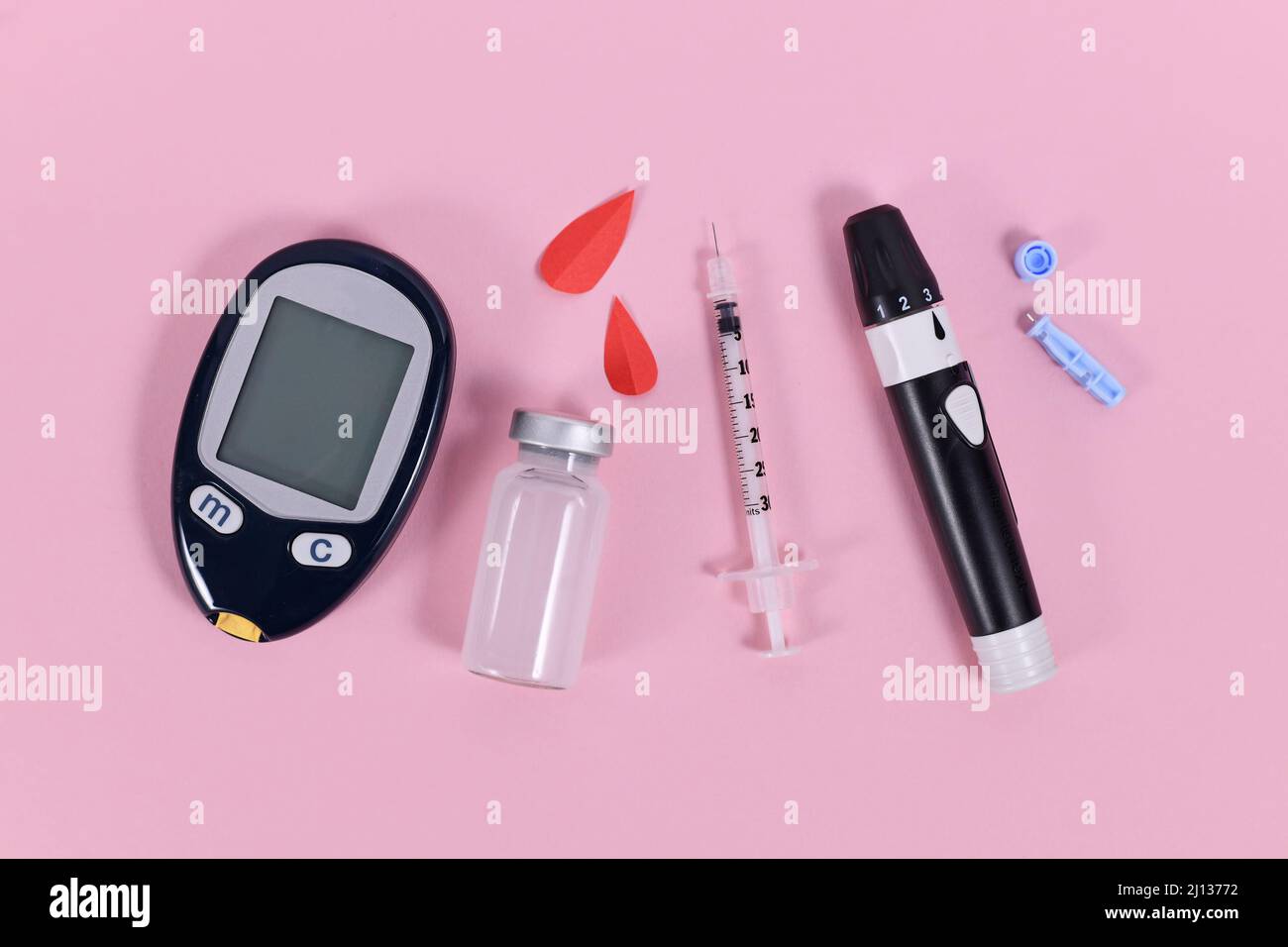 Diabetes treatment equipment with blood glucose sugar meter, lancet, insulin vial and syringe on pink background Stock Photo