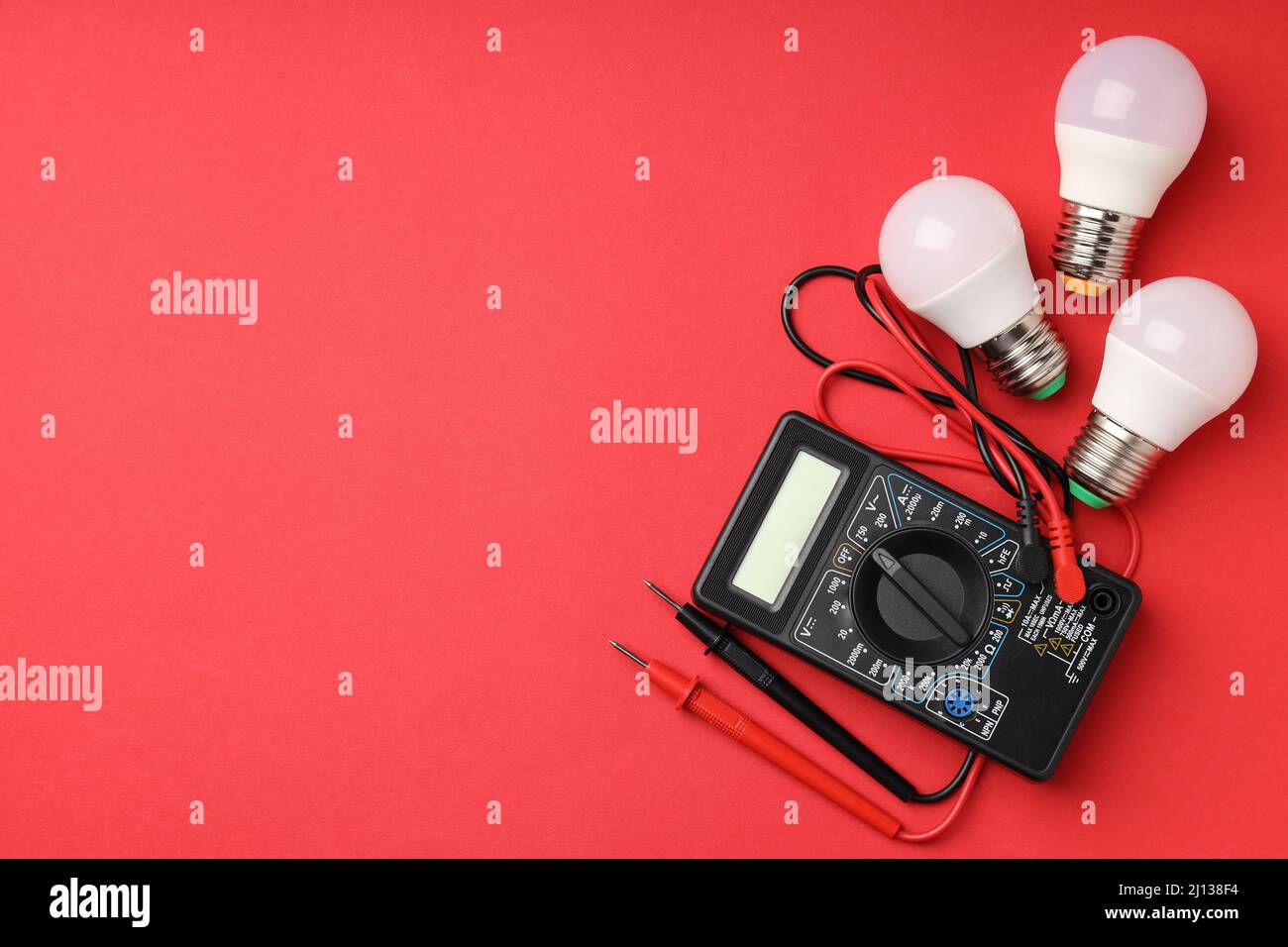Multimeter and energy saving bulbs on red background Stock Photo