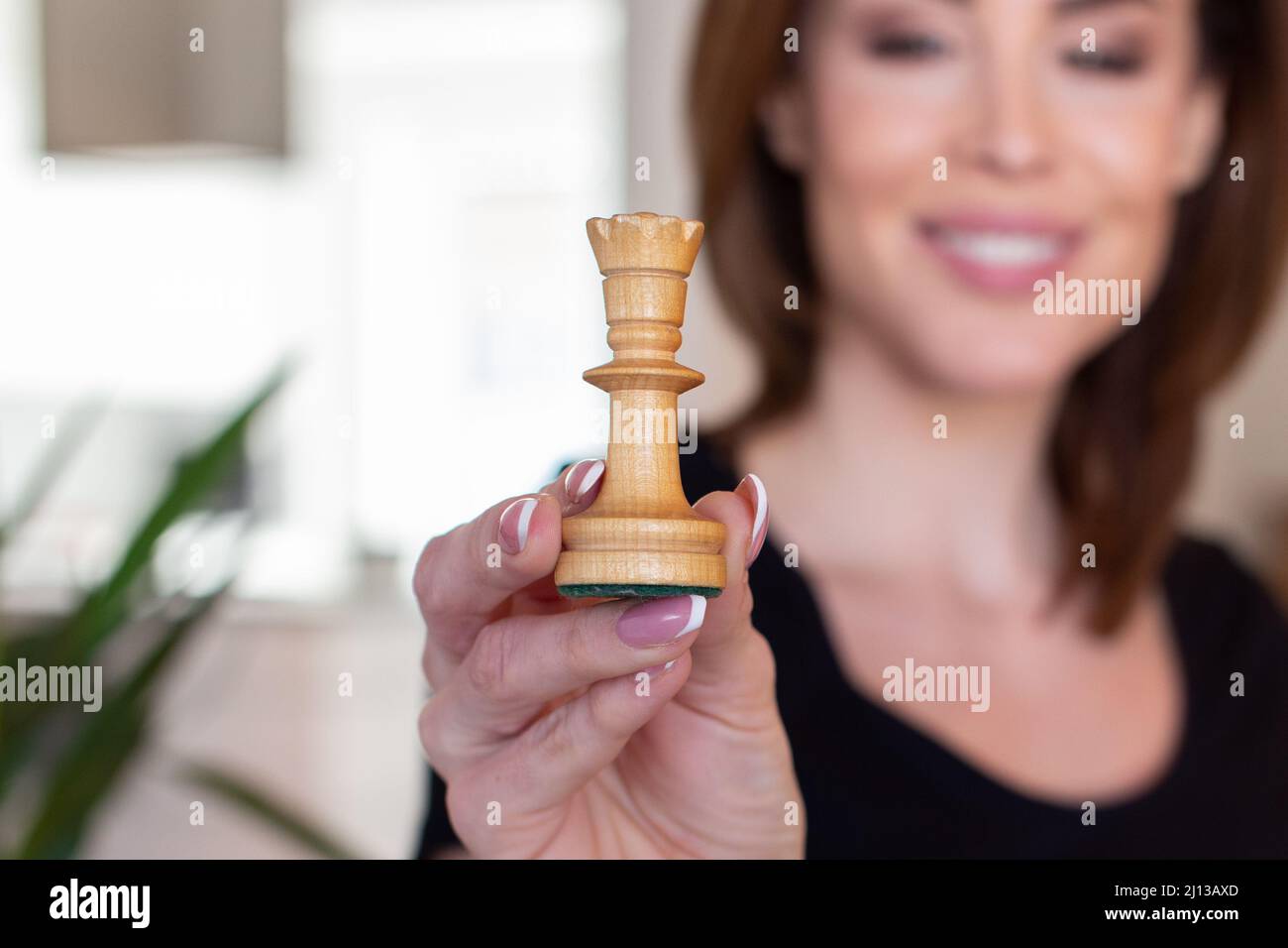 Happy young woman holding chess queen, depth of field Stock Photo