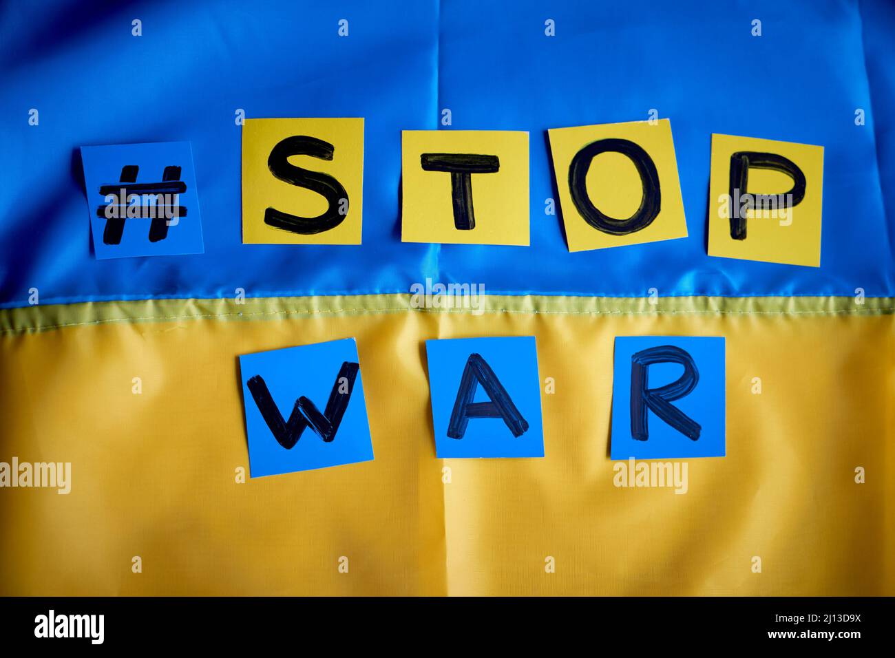 Paper drawn banner Stop War hashtag on Ukrainian flag yellow-blue background. Kids support Ukraine, stay with Ukraine Stock Photo