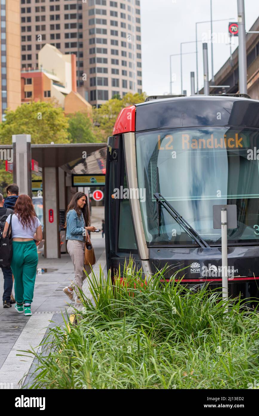 People moving, entering and leaving the light rail trams at Circular Quay, some wearing masks, on a Saturday in Sydney, New South Wales, Australia Stock Photo