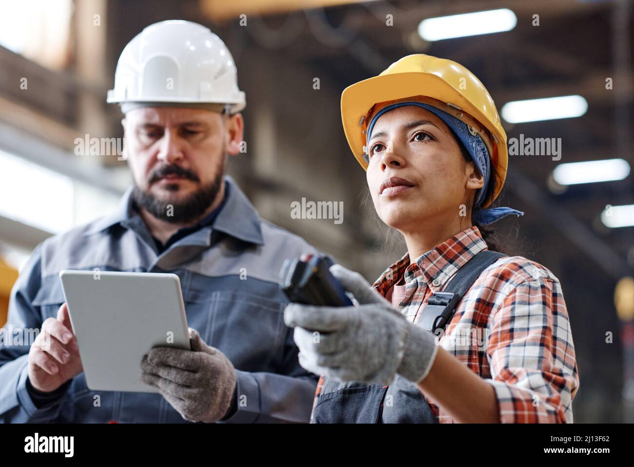 Young Hispanic female engineer in workwear pressing button on remote